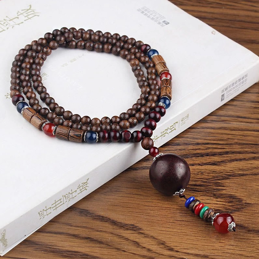 Double-loop Wenge wood beaded necklace with dark round stone pendant and colorful spacer beads on wooden table