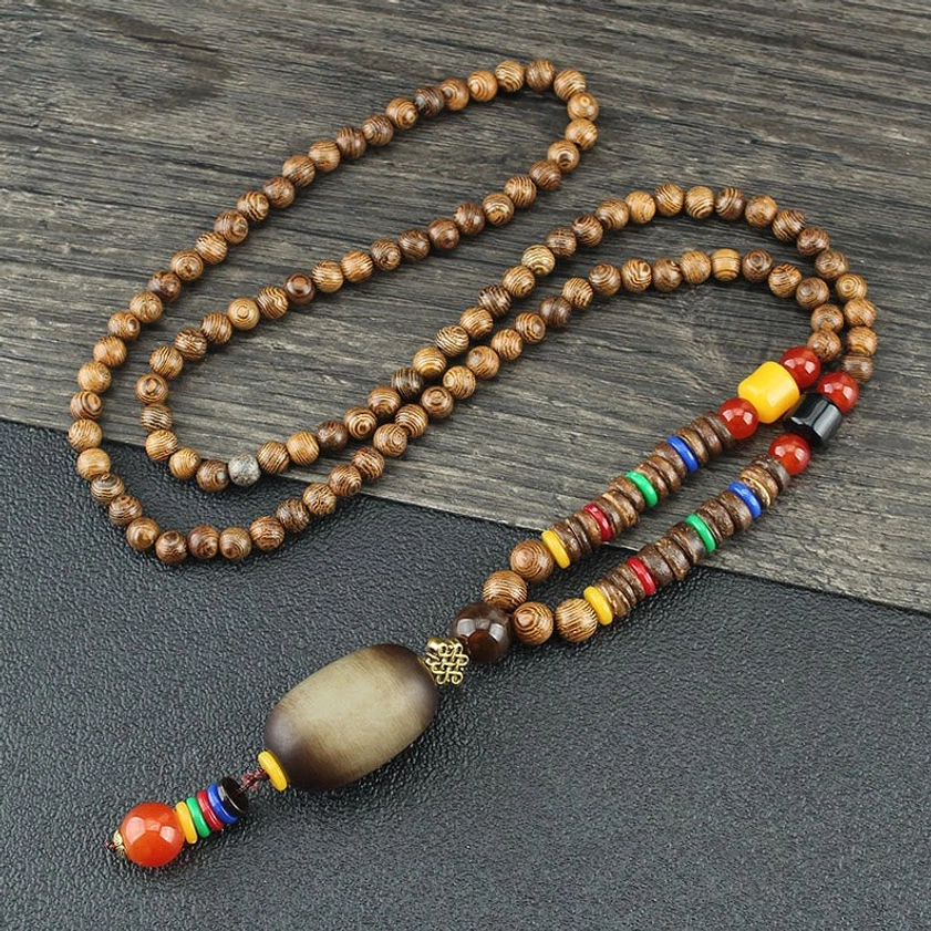 Wenge wood Buddhist necklace with oval matte stone pendant and colorful beaded tassel on grey wooden surface