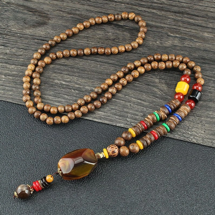 Wenge wood beaded necklace with striped agate pendant and colorful decorative beads on dark wooden tabletop