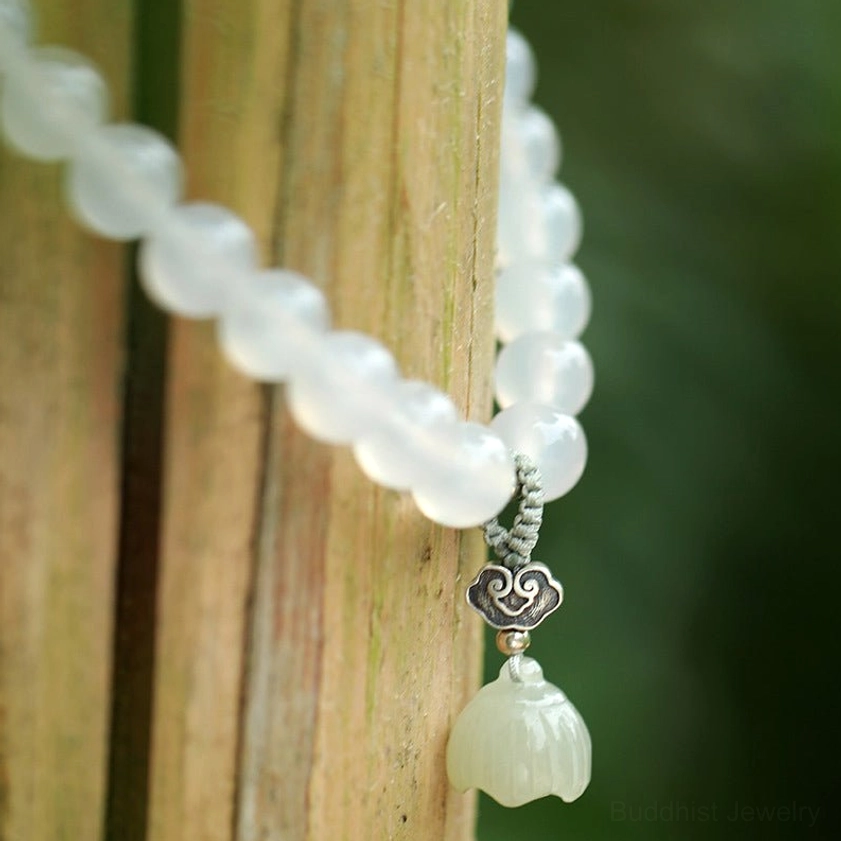 Matte white agate beads with ornate silver clasp and white carved jade lotus pendant side overhead view