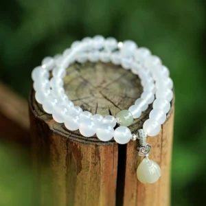White agate jade lotus bracelet double-wrap overhead view with matte beads silver clasp on wooden stump