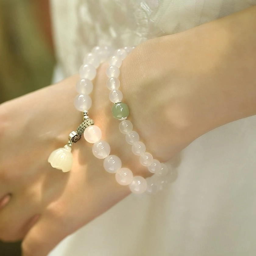 Pair of white agate jade lotus bracelets with mixed green and silver accents held in hands