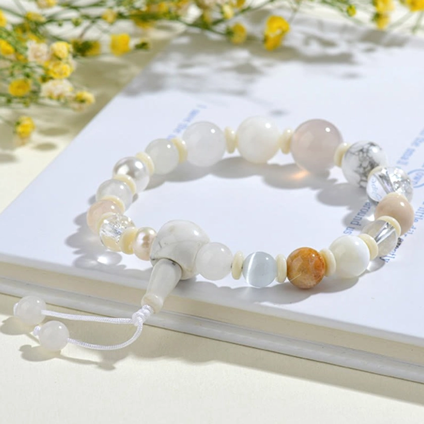 White agate pearl bracelet laid on decorative book with yellow flowers and soft warm lighting