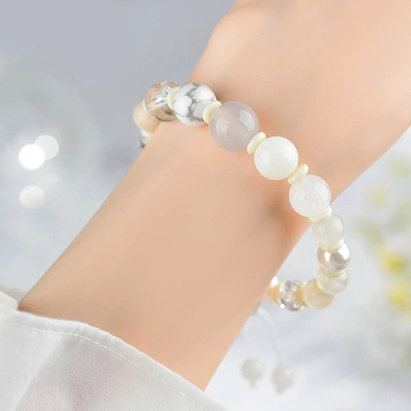 White agate pearl bracelet on right wrist showing warm-toned beads with subtle metallic spacers