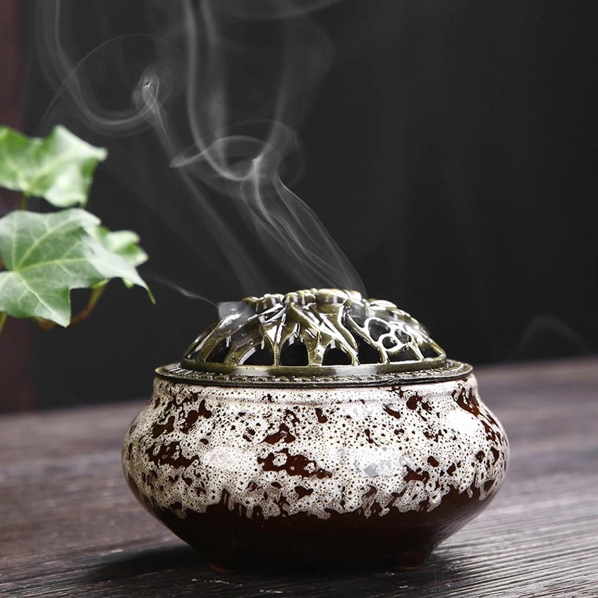 White and brown spotted ceramic Buddhist incense burner with bronze carved lid and smoke emission