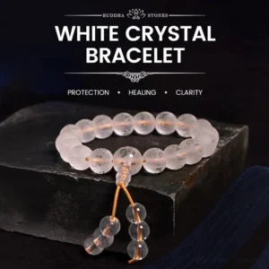 White Crystal Om Mani Padme Hum meditation bracelet with engraved sacred mantra beads and golden tassel cord, displayed on dark wooden stand