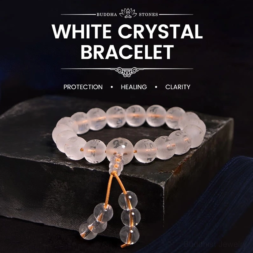 White Crystal Om Mani Padme Hum meditation bracelet with engraved sacred mantra beads and golden tassel cord, displayed on dark wooden stand
