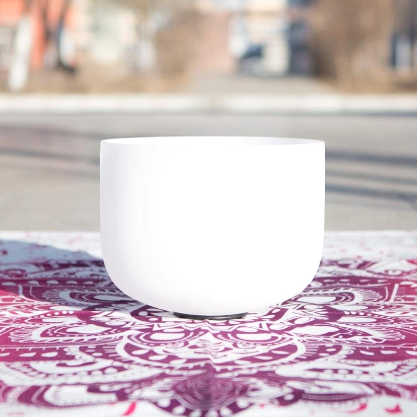 White crystal singing bowl handcrafted for meditation and chakra healing, displayed on mandala cloth with natural outdoor lighting