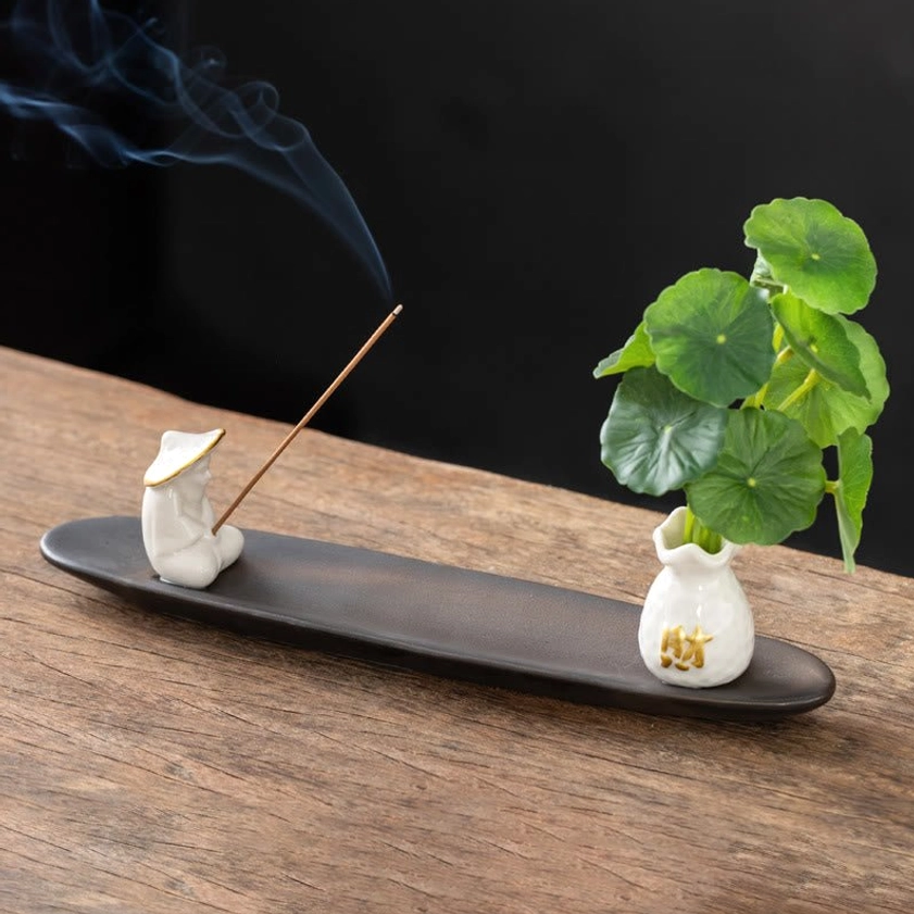 White Fisherman ceramic Buddhist incense burner set with figurine, vase, and penny grass on wooden table
