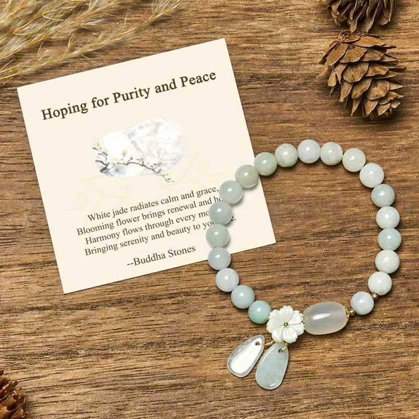 Natural white jade Buddhist bracelet with flower charm displayed on wooden table with greeting card