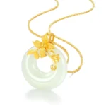White jade Buddhist pendant necklace with copper floral bail on thin gold chain, flat lay on white background showing smooth pale jade donut stone