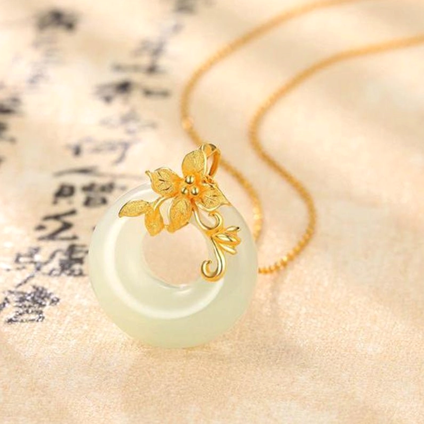 Side profile close-up of jade pendant necklace with light yellow-green stone and decorative copper floral hardware on twisted chain