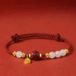 24K gold plated white jade cinnabar lotus bracelet with red adjustable string, front view showing beads and gold lotus pendant