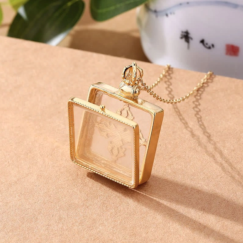 White jade dorje locket necklace angled top-down flat lay highlighting openable locket and gold-tone finish with jade backing
