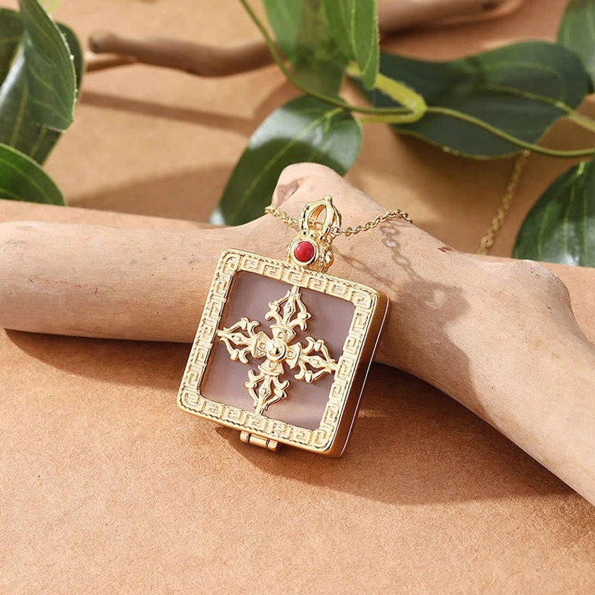 White jade dorje locket necklace worn on wooden hand model with translucent jade inlay and protective red bead accent