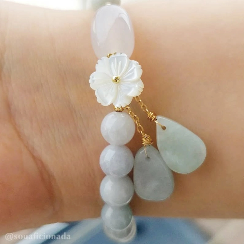 Jade beaded Buddhist charm bracelet with shell flower accent and mixed jade beads with gold hardware on wrist side view