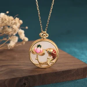 White jade koi fish lotus necklace pendant with gold-plated frame on wooden surface with dried flowers and teal background