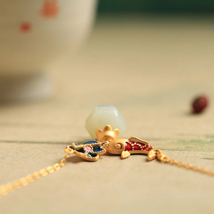 Macro close-up of white jade koi fish lotus pendant showing detailed enamel work, gold hardware, and jade bud charm