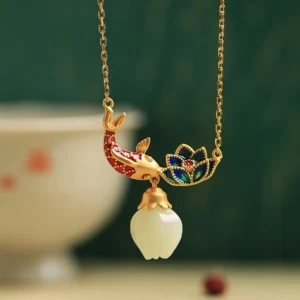 White jade koi fish lotus Buddhist protection necklace with cloisonné enamel pendant displayed on vintage porcelain table setting