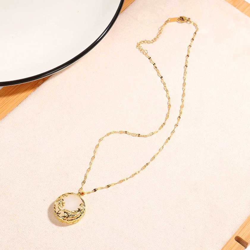 White jade koi necklace full view overhead lay flat with delicate gold chain on beige tabletop