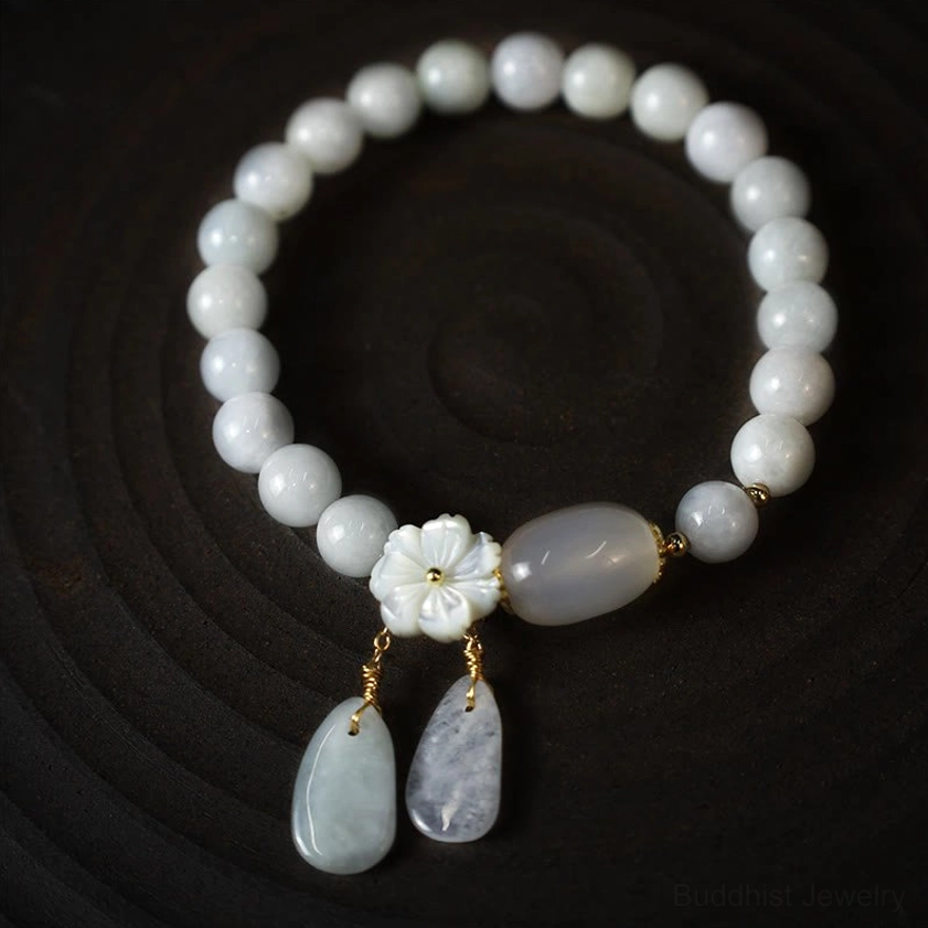 White jade round beaded Buddhist bracelet with central oval jade bead and shell flower teardrop pendants on spiral wooden display top-down