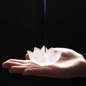White lotus liuli crystal incense burner held in palm, overhead view, frosted glass with detailed petal carving