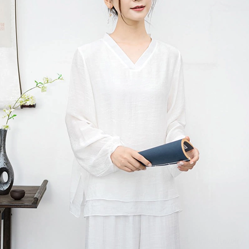Close-up detail of white meditation top showing V-neck, lantern sleeves, and breathable fabric texture
