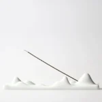 White ceramic mountain peak incense holder with multi-peak design, front view on white background