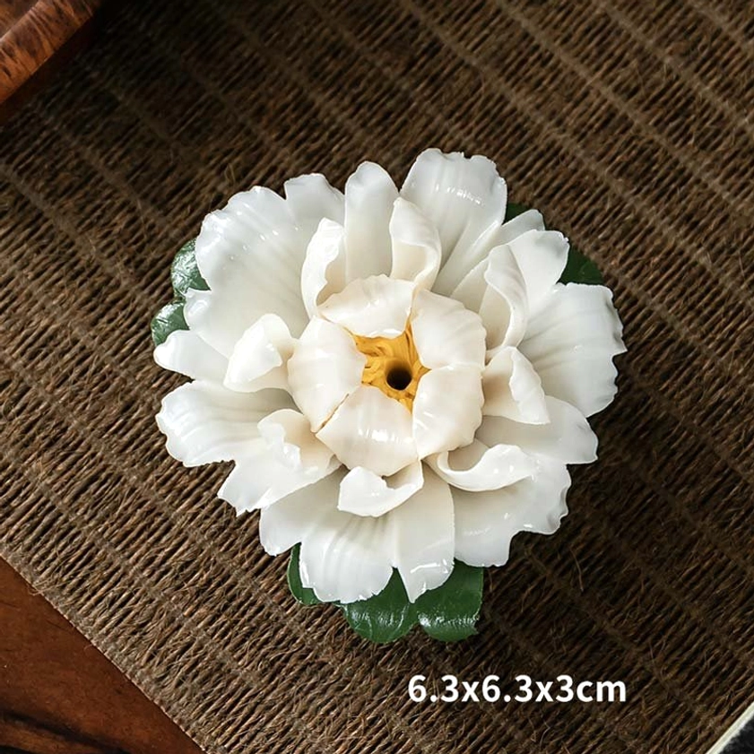 White peony ceramic incense burner with yellow center on woven linen placemat