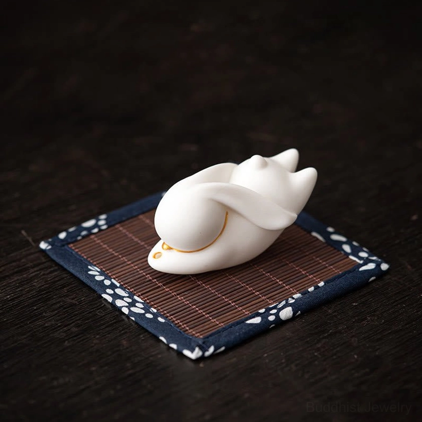White rabbit ceramic incense holder with blue floral bamboo mat on dark wood meditation space