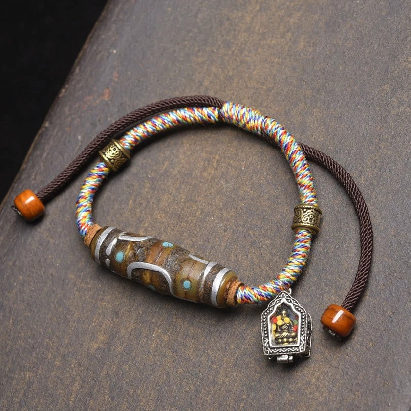 White rope nine-eye dzi bead protection bracelet with colorful decorative beads and metal Buddha pendant overhead display