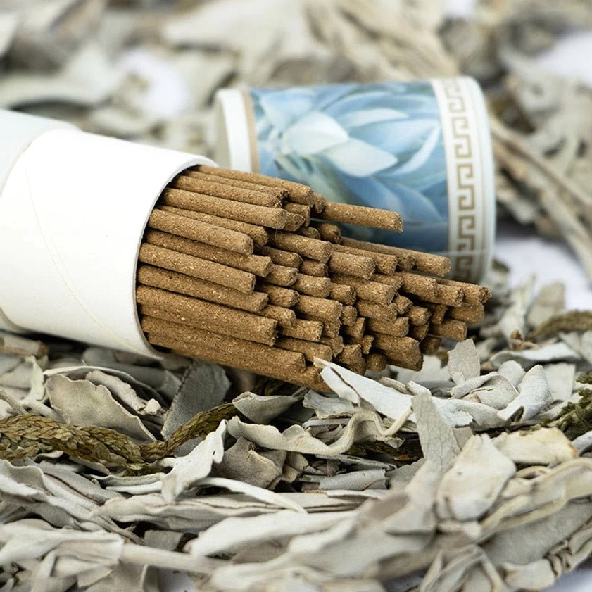 Close-up overhead view of white sage incense sticks loosely arranged with dried sage leaf background