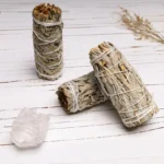 White sage smudge sticks bundle displayed on wooden table with natural cotton twine binding and gray-green dried sage texture