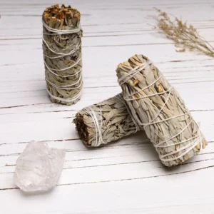 White sage smudge sticks bundle displayed on wooden table with natural cotton twine binding and gray-green dried sage texture