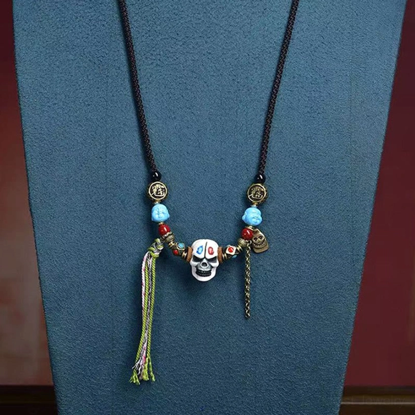 White bone skull Buddhist guardian necklace with black woven cord, blue gemstone beads, spiritual chain, and decorative tassel