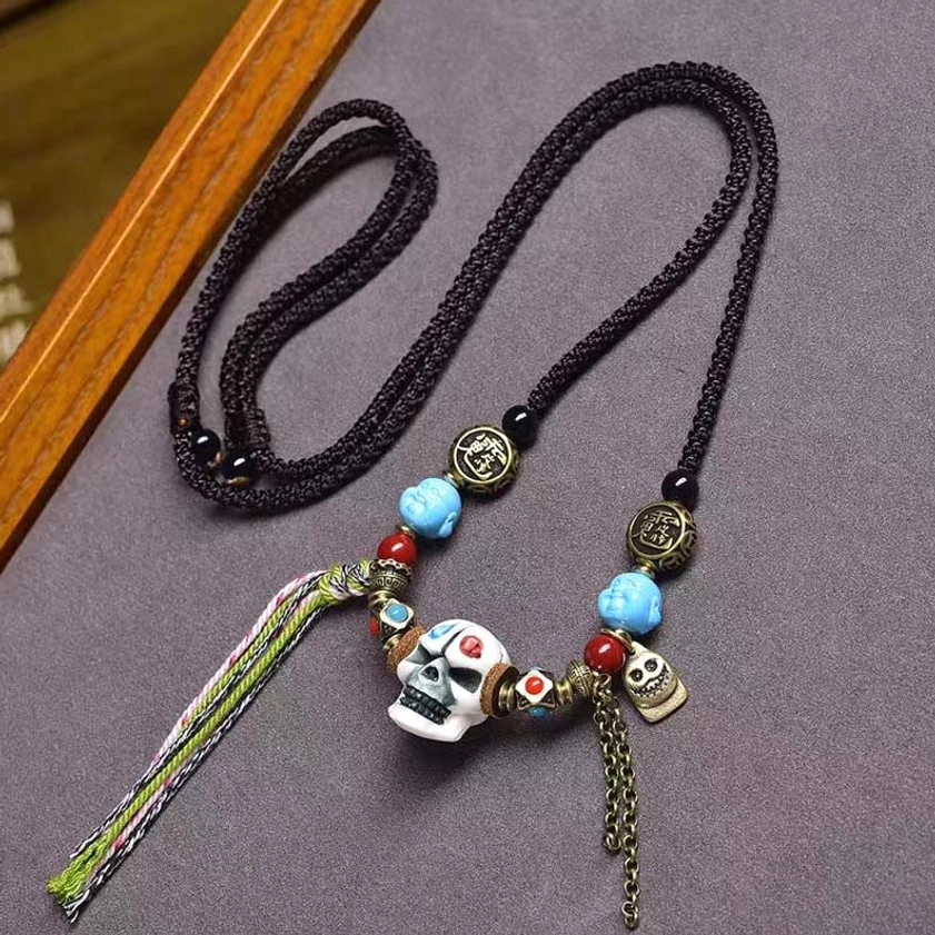 White bone skull Buddhist protection necklace with braided black rope, turquoise agate beads, and spiritual charm accents on display