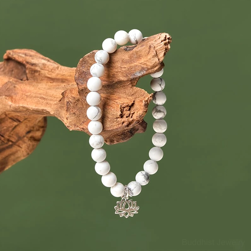 White turquoise lotus bracelet hanging on driftwood showing elastic cord construction and silver lotus pendant