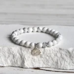 White turquoise lotus sterling silver bracelet featuring polished round beads with 925 silver spacers and lotus charm on white stone background