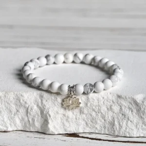 White turquoise lotus sterling silver bracelet featuring polished round beads with 925 silver spacers and lotus charm on white stone background