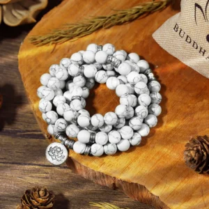 White turquoise lotus mala bracelet handmade 108 beads with silver spacers and lotus charm pendant on wooden table with dried botanicals and brand pouch