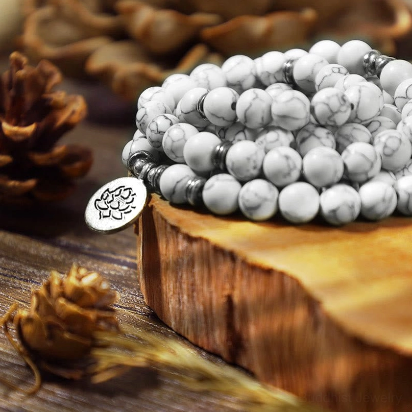 Stacked white turquoise mala beads close up side view showing grey veining natural stone texture and silver lotus charm