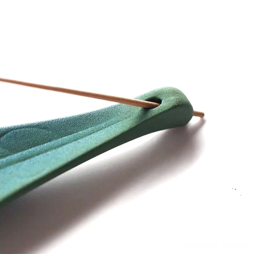 Matte green ceramic incense holder with incense stick inserted in end slot