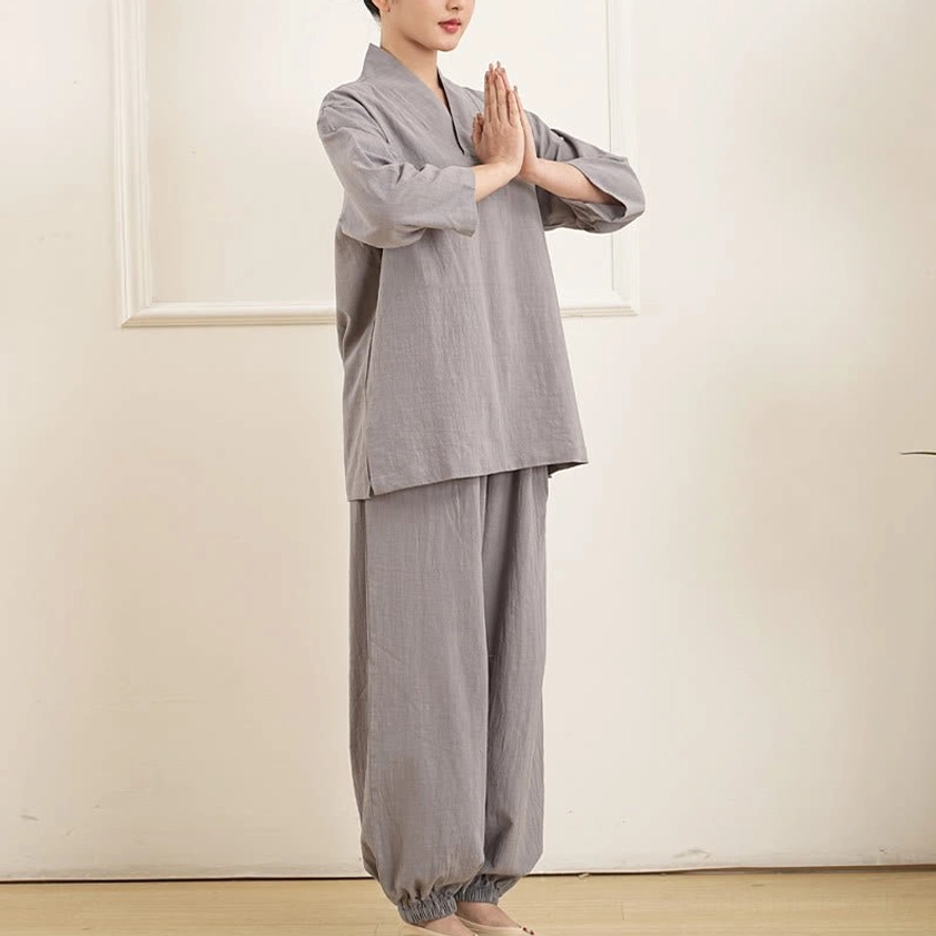 Women in gray cotton tai chi meditation clothing standing in prayer mudra pose indoors