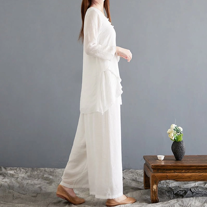 Left side view of women's linen meditation two-piece set showing silhouette of loose asymmetrical top and floor-length wide-leg pants in natural off-white