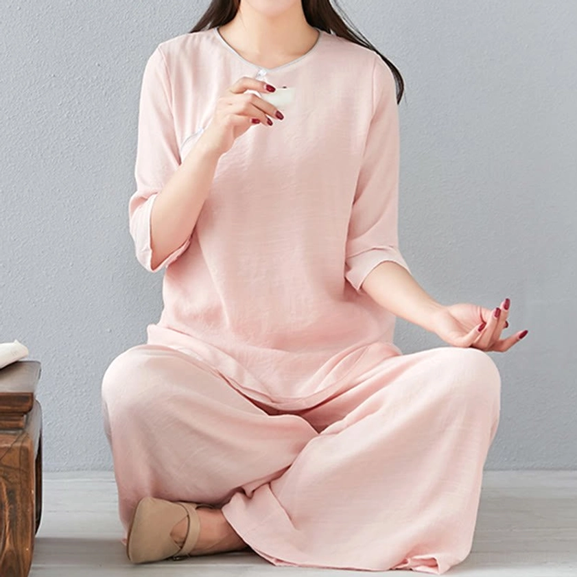 Full-length side view of model in white meditation cotton linen long-sleeve top with floor-length wide-leg pants
