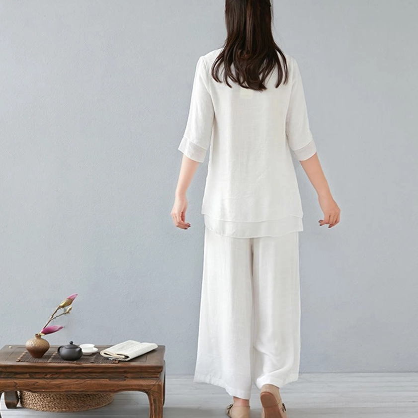 Back view of woman wearing white meditation cotton linen two-piece set showing loose fit wide-leg pants and top silhouette