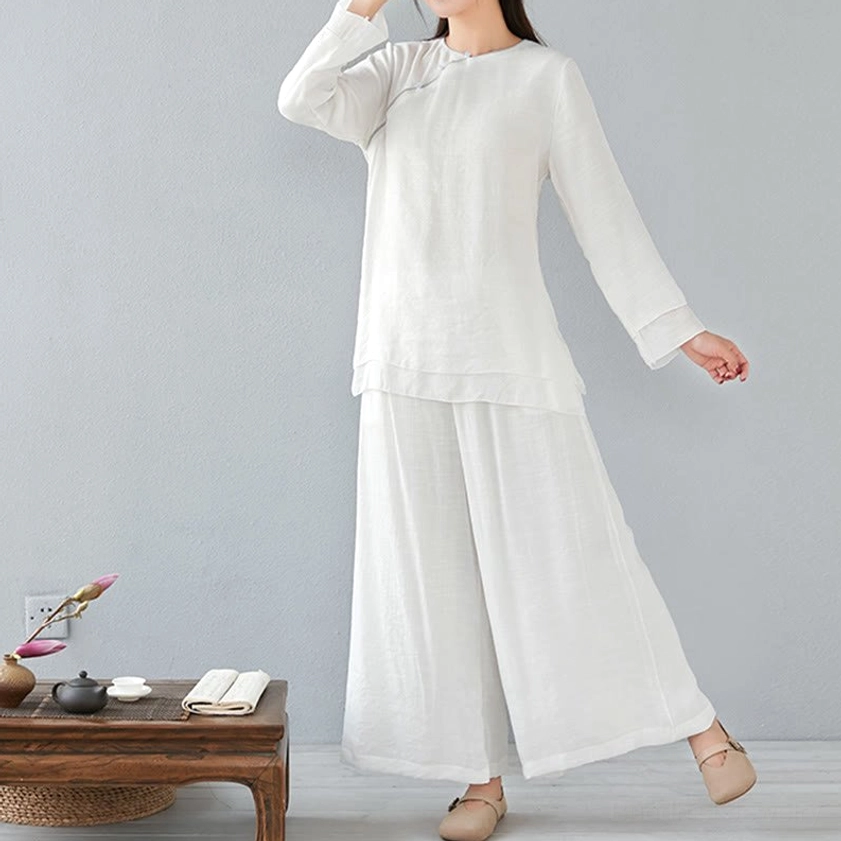 Dynamic front view of woman in white loose meditation cotton linen top and wide-leg pants with raised hand, Chinese home tea room