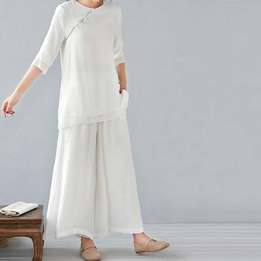 Side full-body view of woman wearing pure white three-quarter sleeve meditation linen top and loose wide-leg pants, minimalist studio background