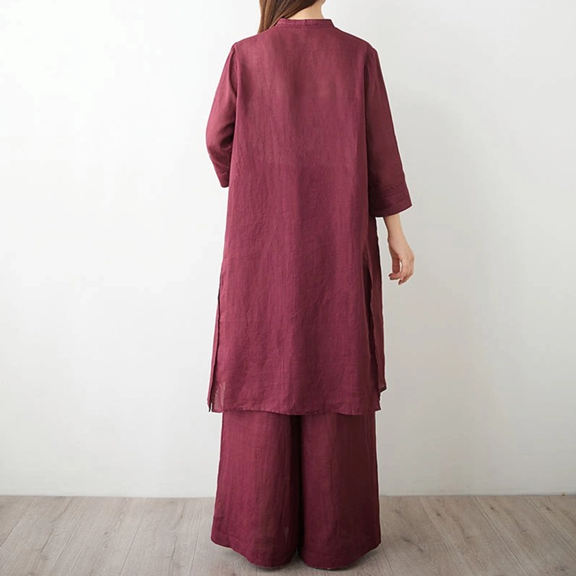 Back view of women's burgundy linen meditation clothing set showing asymmetrical long top and wide leg pants