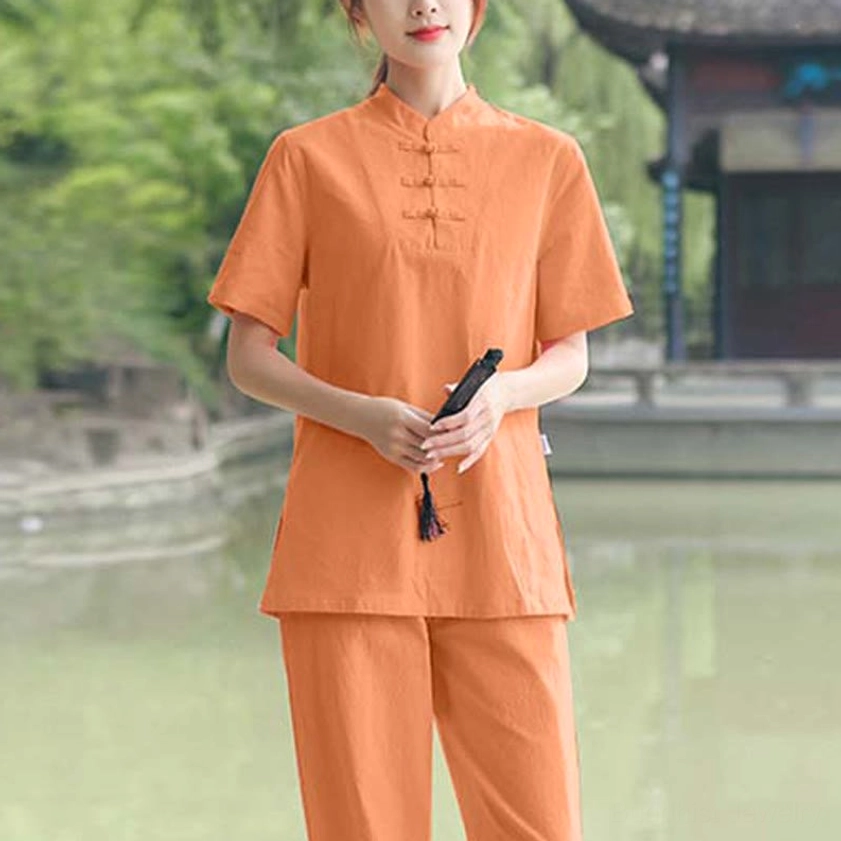 Tangerine orange cotton-linen tai chi clothing set front three-quarter view with frog buttons in traditional Chinese garden